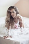 stripteaseuse blonde pose en lingerie blanc dans un lit à Angers